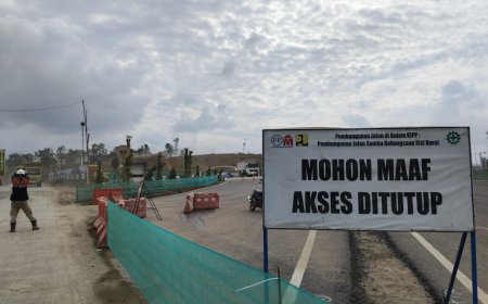 Pekerja kontruksi, Wiwin (kiri) saat mengatur lalu lintas kenderaan berat yang akan masuk KIPP IKN. (Foto: Khairul Arief/Nusantaraterkini.co)