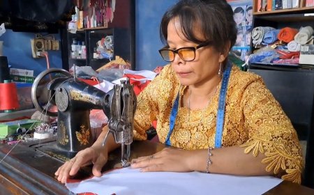 Mak Ivo, pengrajin bendera merah putih saat tengah menjahit bendera dengan mesin tuanya. (Foto: Alfi/nusantaraterkini.co)